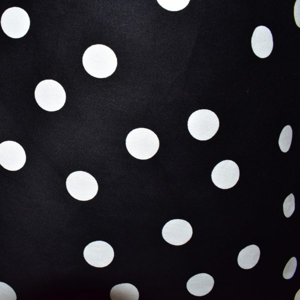 Close up of fabric with large white polka dots on black background